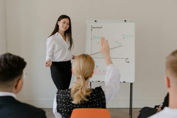 A businesswoman leads a meeting with a graph presentation, engaging her audience. Professional setting.