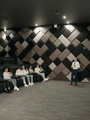 A group attentively listens to a business presentation in a modern, stylish auditorium.