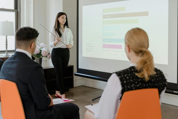 A young professional presenting data in a modern office to attentive colleagues.